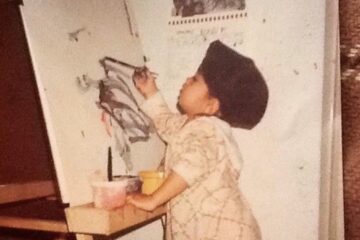 A photo of maria at a young age standing and painting on a canvas.